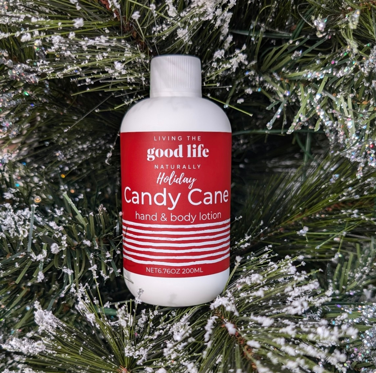 Snowy Christmas limbs with a handmade bottle of Candy Cane Lotion with a red label