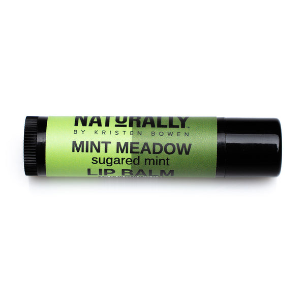 A brown lip balm tube with a green label. The label reads “Naturally by Kristin Bowen, Mint Meadow, Sugared Mint, Lip Balm”.