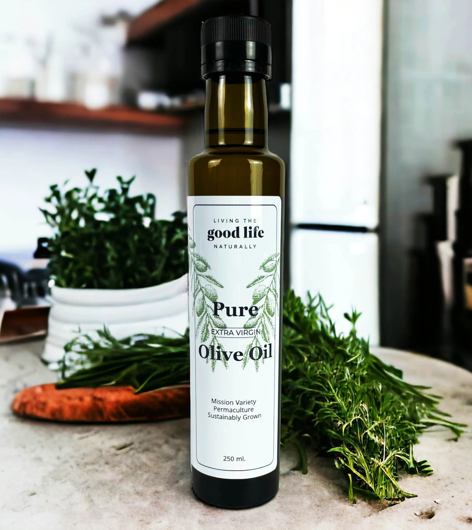 a bottle of pure extra virgin olive oil by 'living the good life naturally' with kitchen background